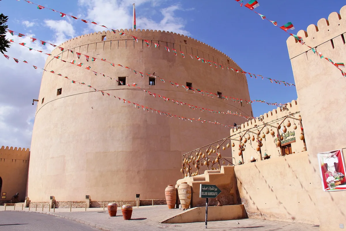 Nizwa Fort's round tower, hung with Omani flags